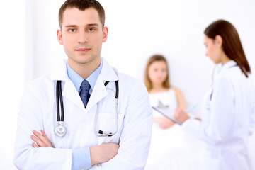 Friendly male doctor on the background with patient in the bed