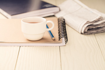 Hot tea cup on a notebook on a white wooden table.