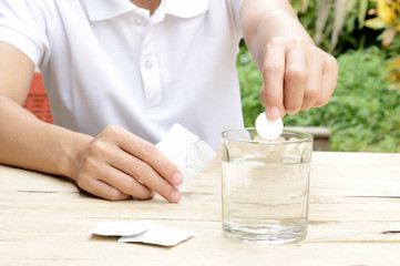 woman dropping effervescent tablet in glass of water