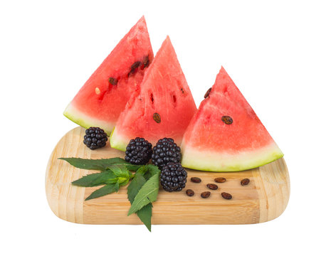 The triangular slices of watermelon, seeds, blackberries and mint. On a wooden board. Isolated on white background.