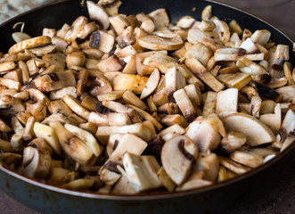 Preparation of fried mushrooms and onion in a frying pan