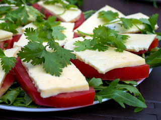 Appetizer of tomato sprinkled with cheese and herbs