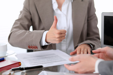Group of business people or lawyers at meeting  discussing contract papers. Woman showing thumb up