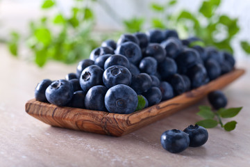 blueberries with green leaves in wooden dish