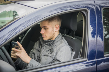 Handsome Young Man using mobile phone while driving a car