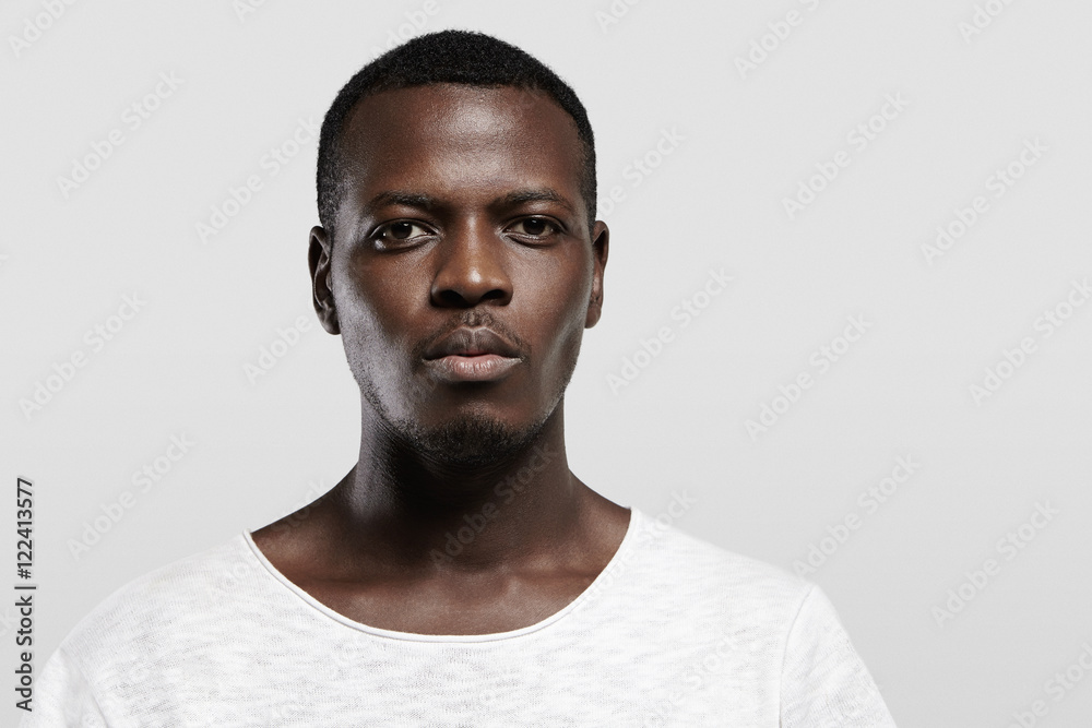 Wall mural headshot of attractive serious african student with small beard and moustache, dressed in casual t-s