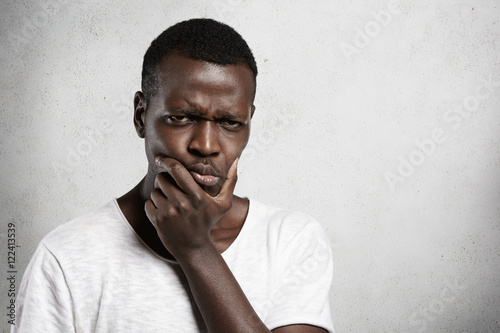 “Portrait of skeptical African young man looking with suspicious or