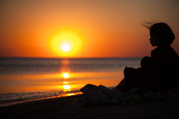 Fototapeta premium The child looks at the sea sunset