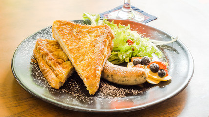 Ham cheese French toast serve with grilled sausage, salad, blueberry, strawberry and topping with icing sugar