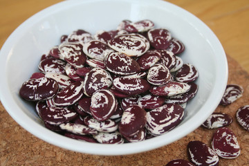 fagioli piatti secchi bianchi e rossi in una ciotola bianca su tavolo di legno