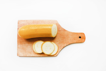 Sliced fresh yellow squash vegetable marrow on wooden cutting board isolated ob white table background Nutrition food product home cooking for health benefits