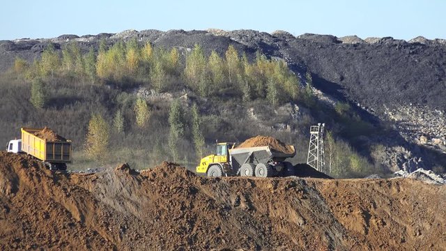 URGUN, RUSSIA - SEPTEMBER 26, 2016: Haul trucks BelAZ conceal ground on open coal quarry Urgunsky in Iskitim District of Novosibirsk Region, Siberia, Russia