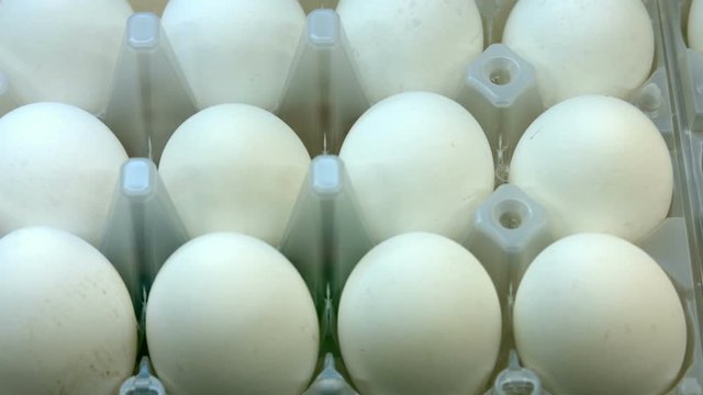 A lot of white chicken eggs. The goods are on a supermarket shelves
