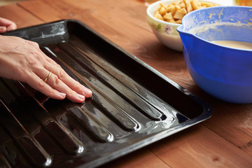hand lubricates the baking dish