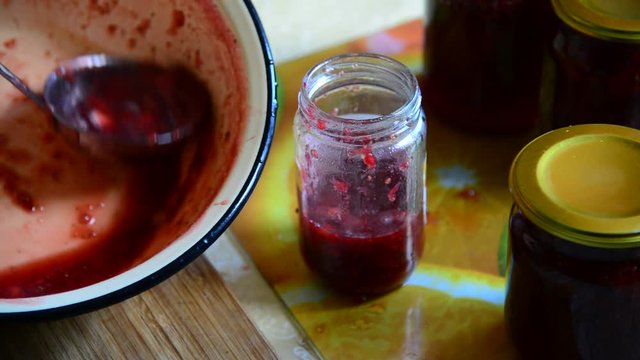 Woman puts handmade Strawberry jam in jar