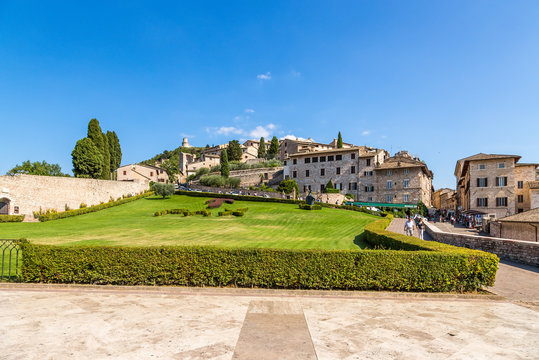 Assisi, Italy. The city view with the lawn in front of St. Francis Cathedral: Tau cross and motto of the Franciscan &laquo;Pax et Bonum&raquo;