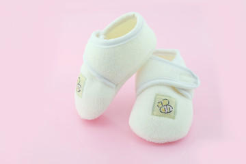 Baby shoes on light pink background