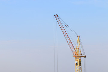 Fototapeta na wymiar Part of yellow stationary hoist on construction site, blue sky a