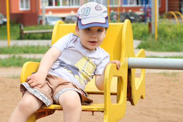 Little cute happy boy rides on carousel on playground at summer
