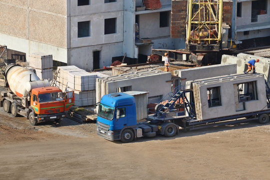 Concrete mixer, truck, workers on construction site with new bui