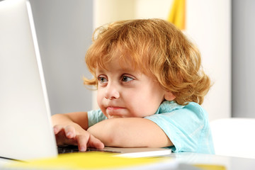 smiling redhead boy playing with computer