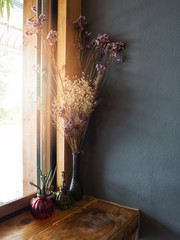 Dried flowers in vase on table beside windowsill, vintage tone