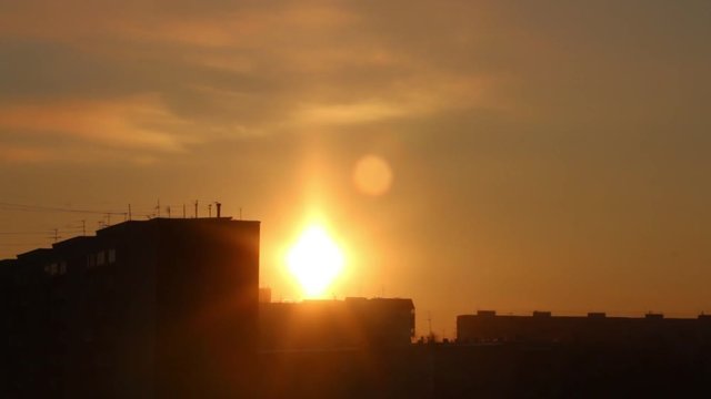 Bright sunset and silhouettes of residential buildings, time lapse