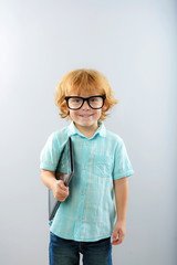 child in glasses with portable computer isolated on grey