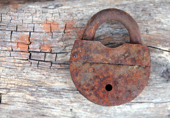 Old rusty lock on a wooden background