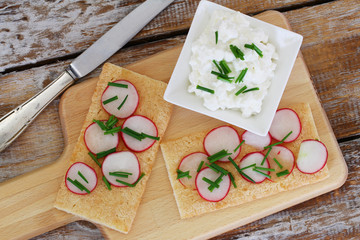 Breakfast consisting of crisp bread with fresh radish and bowl of cottage cheese
