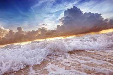 Sea waves on the sunset cloudy sky background