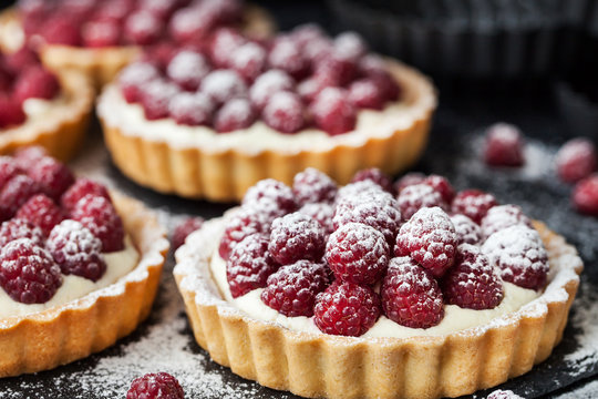 Delicious raspberry mini tarts on dark background
