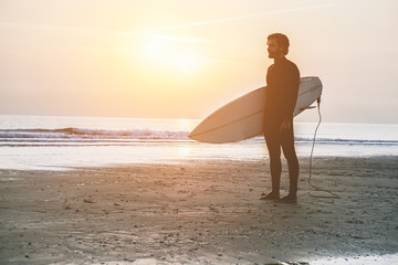 Silhouette of surfer standing on the beach waiting for waves