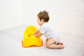 Infant child baby boy toddler play with potty toilet stool pot on a white background - obrazy, fototapety, plakaty