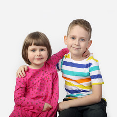 Little boy and girl sit embraced on gray background in square - love and friendship concept