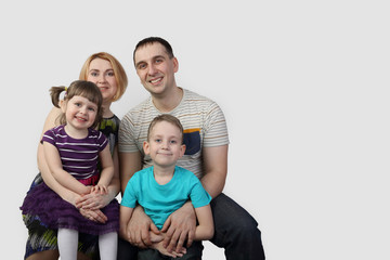Full family portrait on gray background with copy space for text - Man, woman, boy and girl - happy parenthood