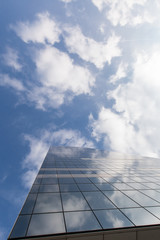 Modern office building on sky background with clouds reflection