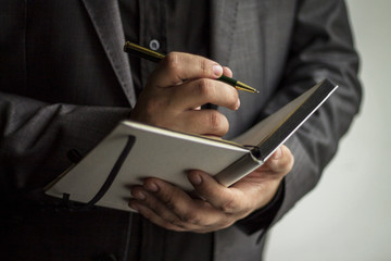 Unrecognizable business person taking notes in personal organizer