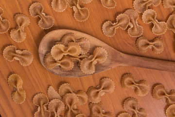 Wholegrain Farfalle into a spoon. wholemeal. Integral.