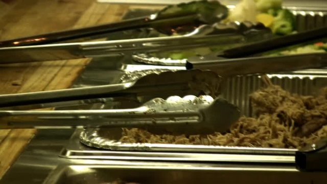A 26 second clip of people serving Hawaiian food from hot trays. HD 1080i.
