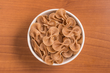 Wholegrain Farfalle into a bowl. wholemeal. Integral.