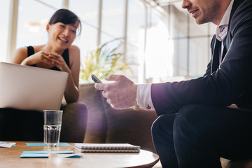 Fototapeta premium Young business man using mobile phone in meeting