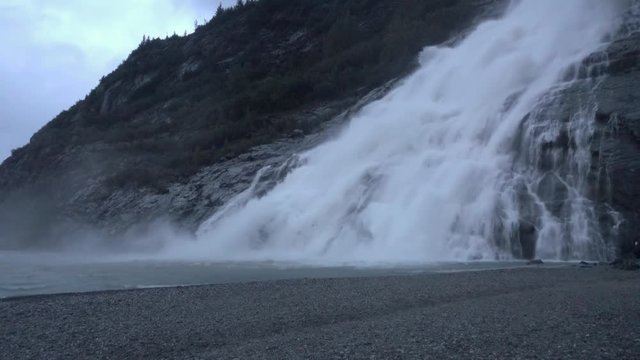 An establishing shot of a Mendenhall Glacier waterfall near Juneau, Alaska on a foggy day.  	