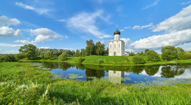 Wide angle view of the Intercession church on Nerl river near Vladimir and its reflection in swamp with cloudy sky reflections, Russia