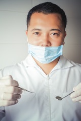 Asian dentist doctor holding instruments. Dental clinic. Implant procedure