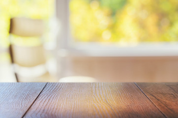 Wood table top on colorful blurred interior background. Fall view outside the window. Can be used...