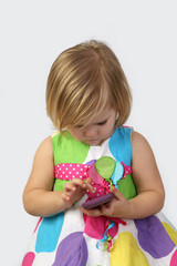 Little girl plays with cell phone close up on gray background