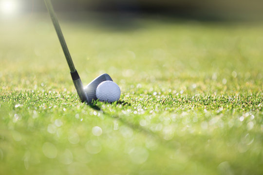 Golfer hitting iron club on golf course on fairway.