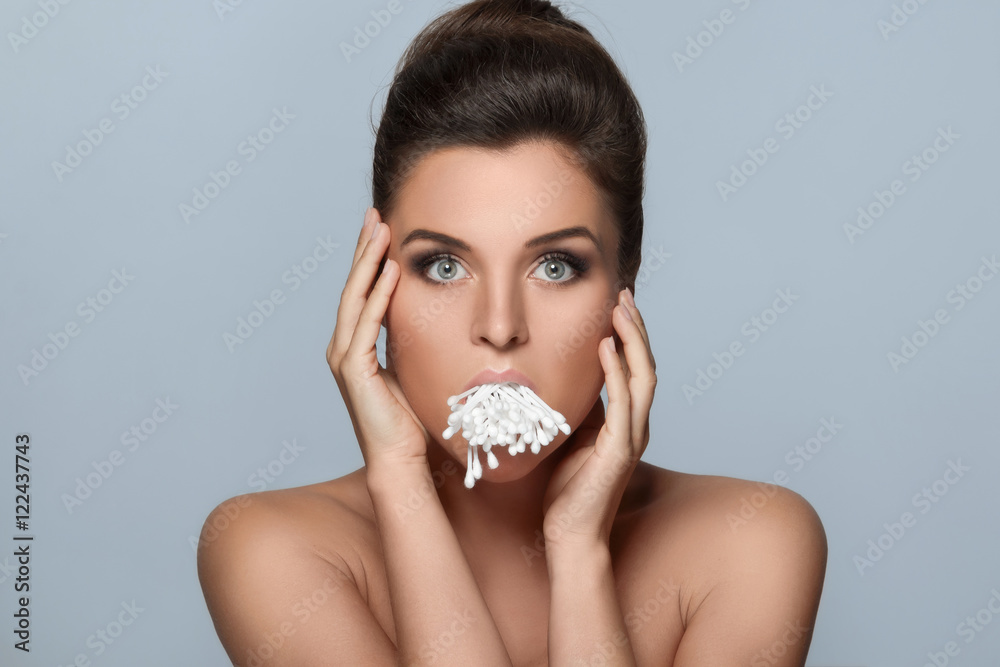 Wall mural Young woman with a full mouth of cotton swabs