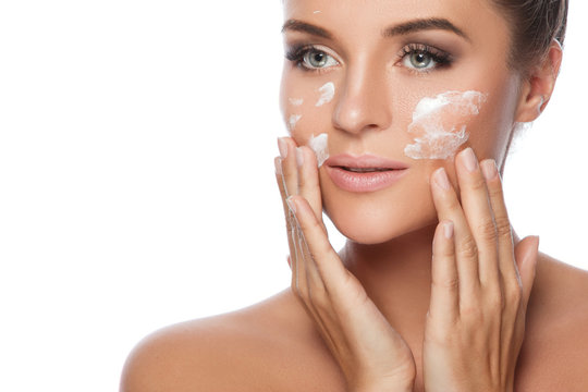 Young and beautiful woman applying moisturizing cream on her fac